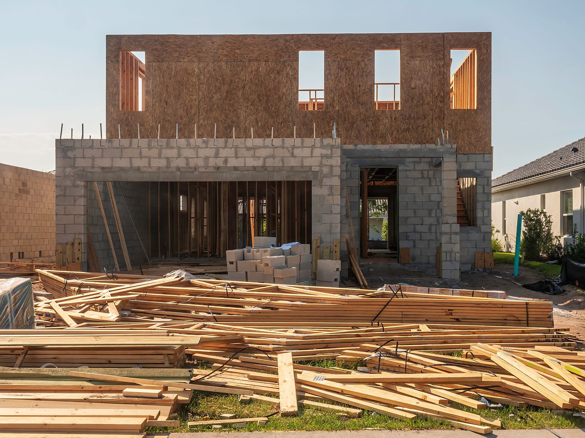 A house is being built with a lot of wood in front of it.