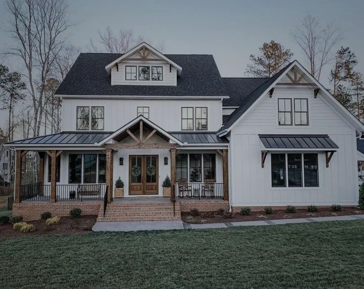 A large white house with a black roof and a large porch