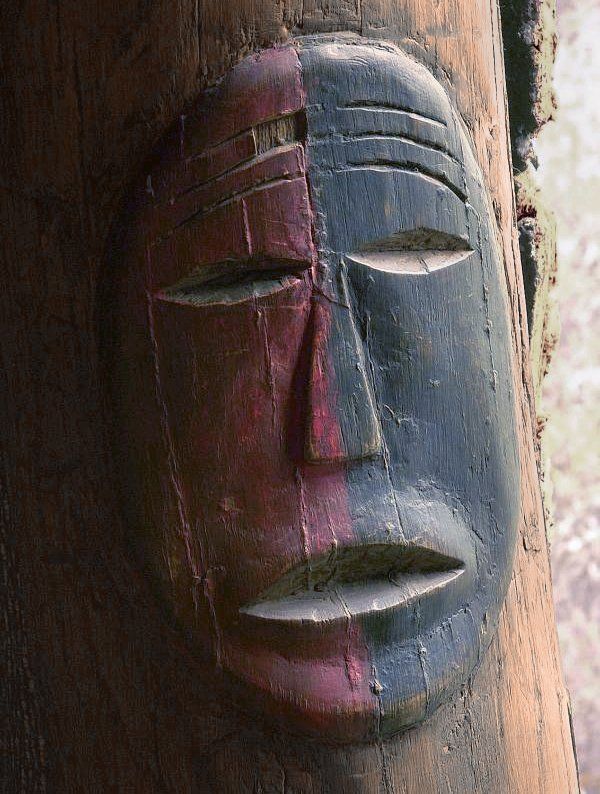 A statue of a face is carved into a tree trunk
