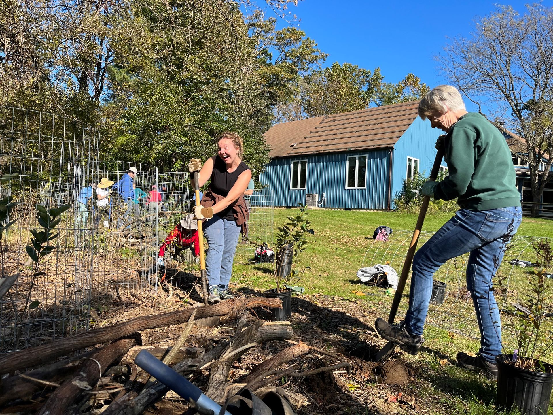 A group of people are working in a garden in front of a house.
