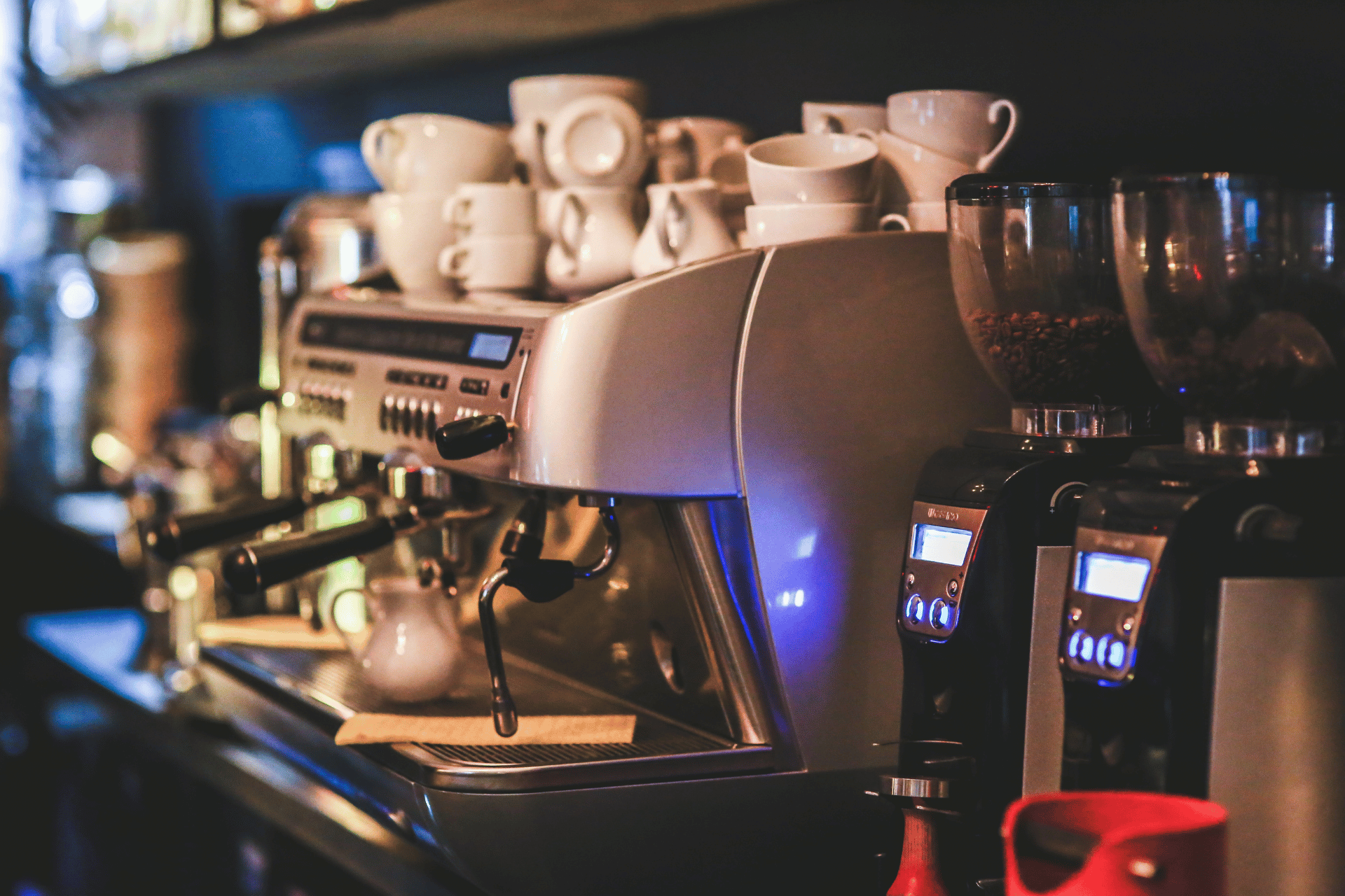 A coffee machine filled with cups and glasses is sitting on a counter.