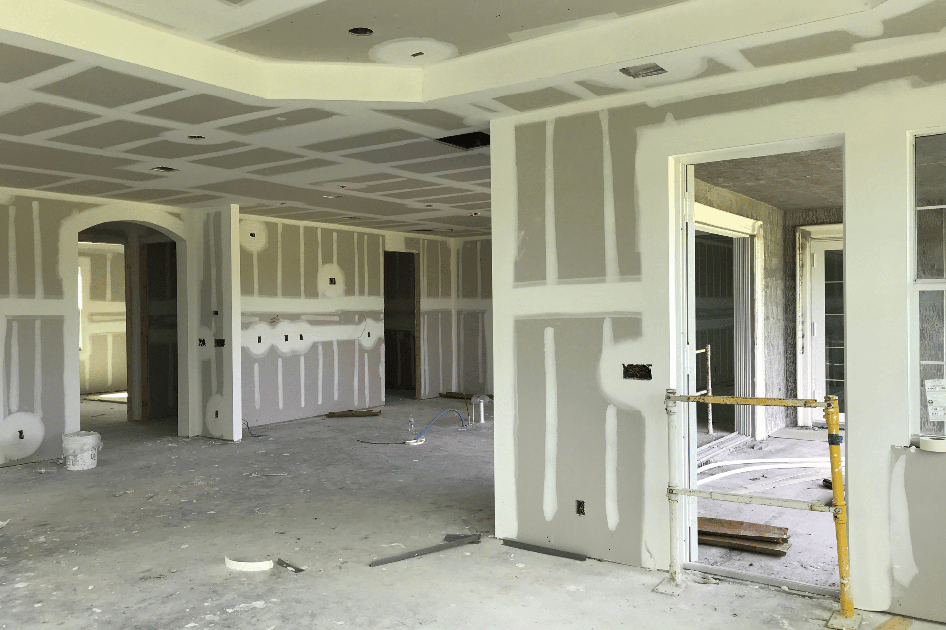 An empty room with drywall on the walls and ceiling with mud and tape