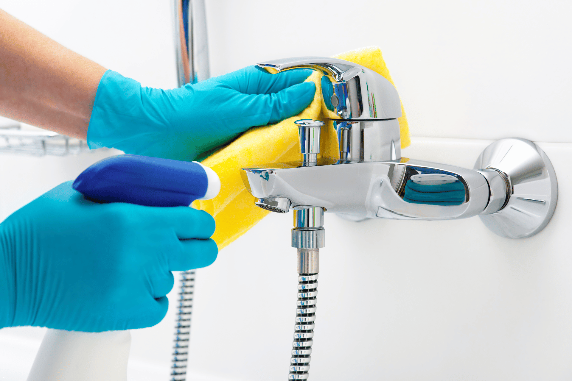 A person is cleaning a shower head with a sponge and spray.