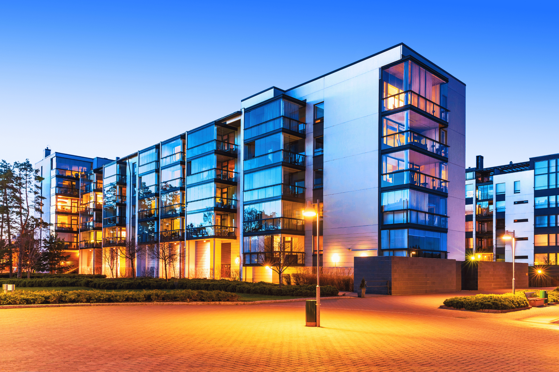 A large apartment building with a lot of windows is lit up at night.