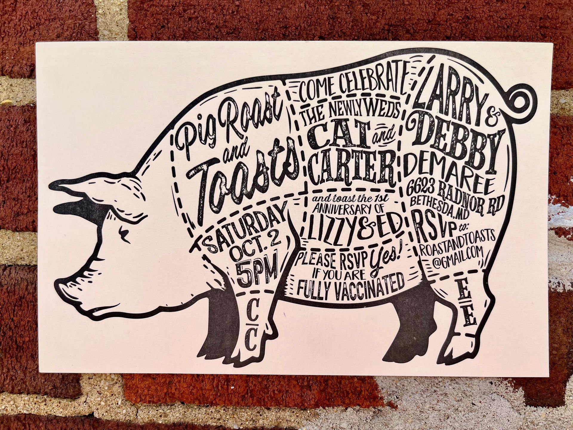 an letterpressed stylized invitation for a pig roast and toast is on a brick wall