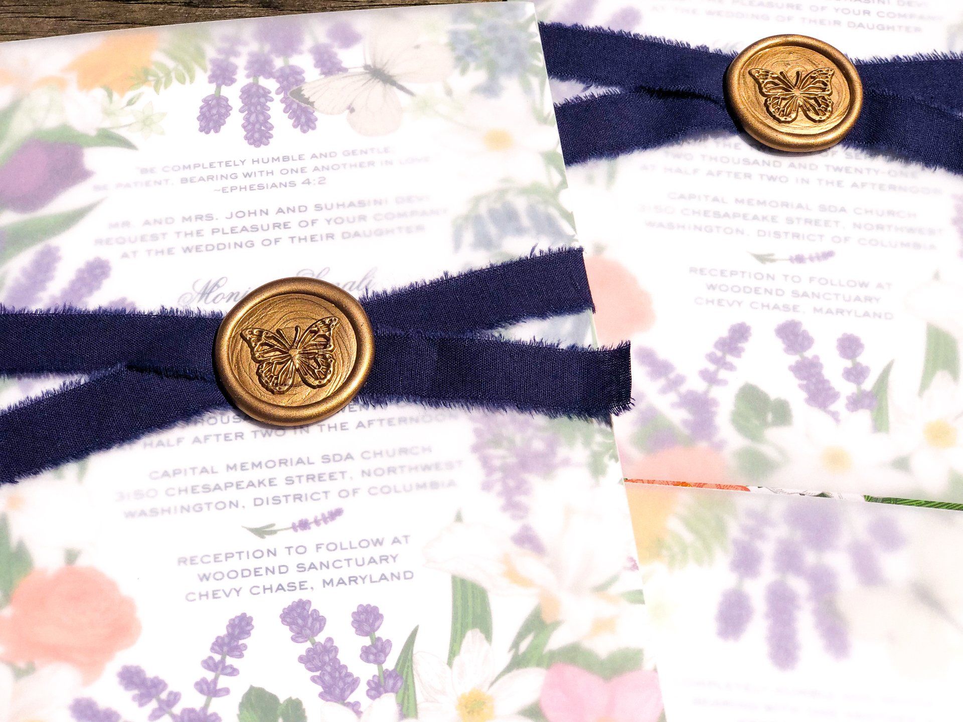 a wedding invitation with a butterfly wax seal, silk ribbon tie and vellum wrap