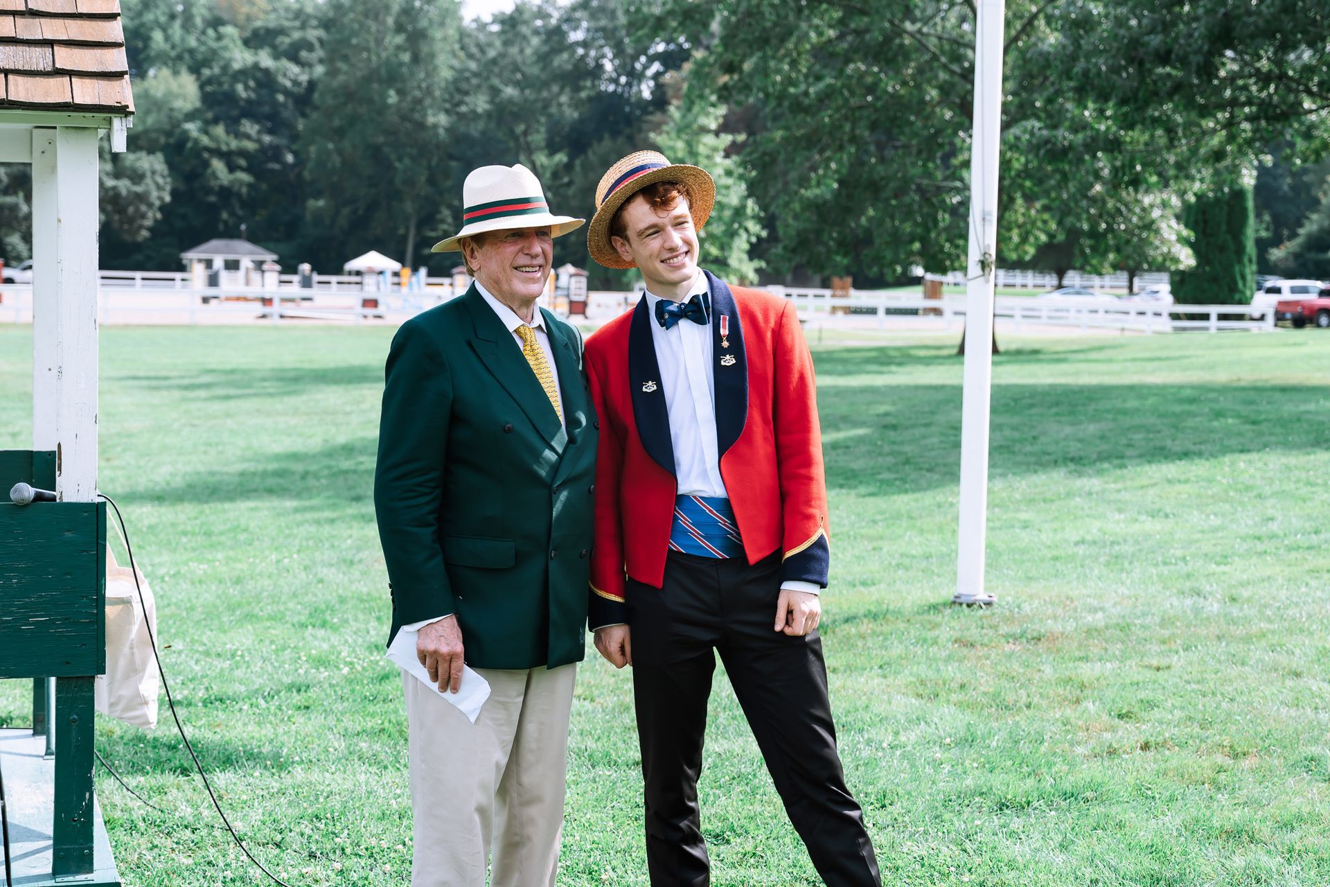 Two men are standing next to each other in a grassy field.