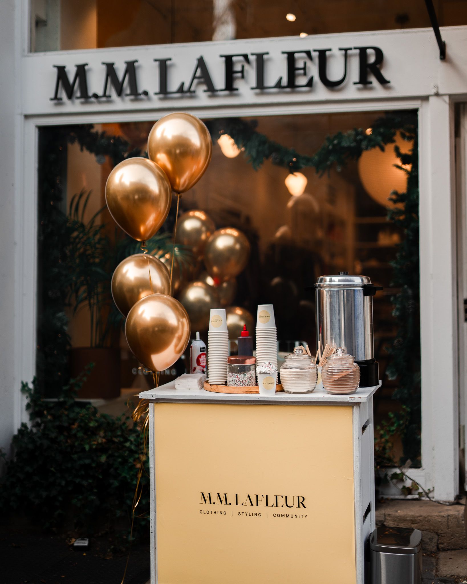 A store front with balloons and cups in front of it.