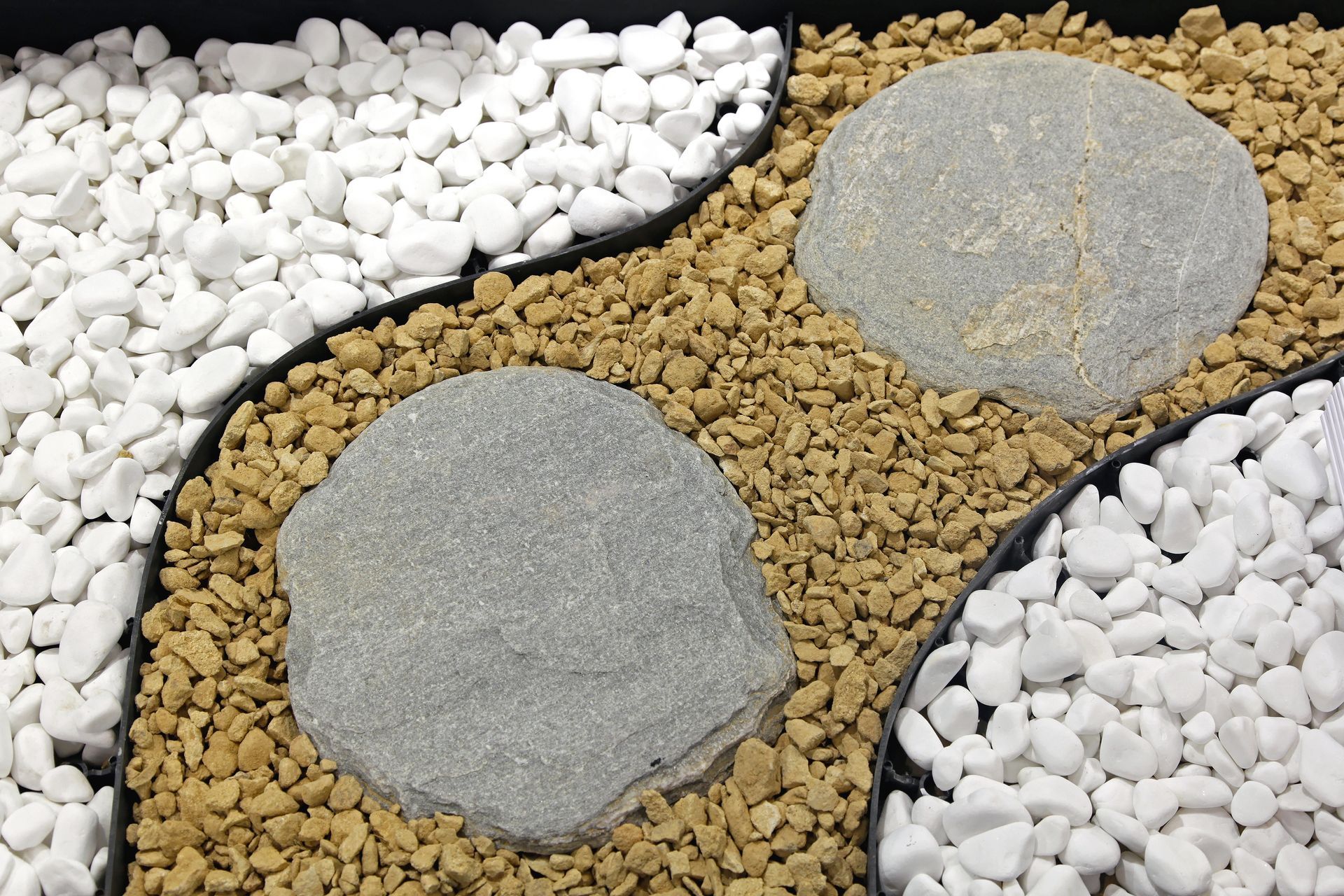 Decorative garden bed with white and tan gravel, gray stepping stones.