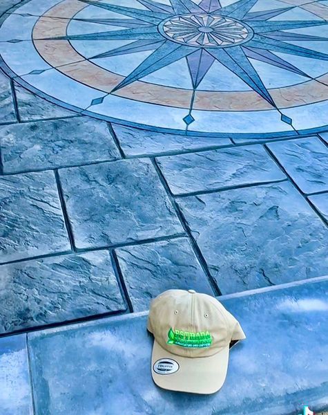 Tan cap rests on textured blue stone patio with compass rose design.
