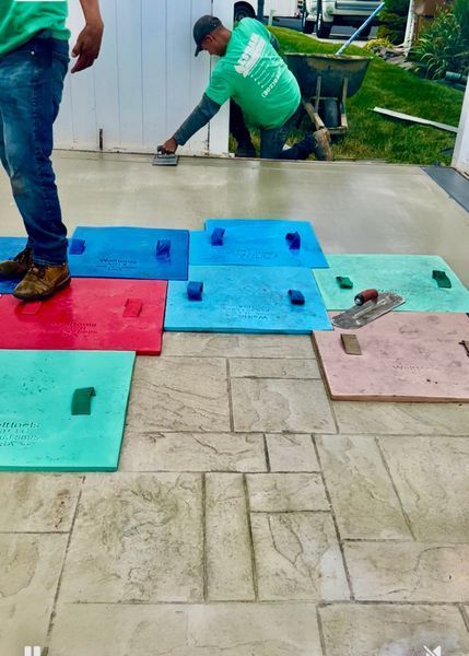 Workers stamping concrete patio with colorful molds.