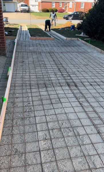 Driveway under construction; rebar grid laid, workers in background.