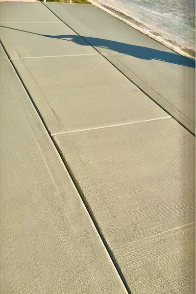 Concrete sidewalk with expansion joints, shadow cast from top right.