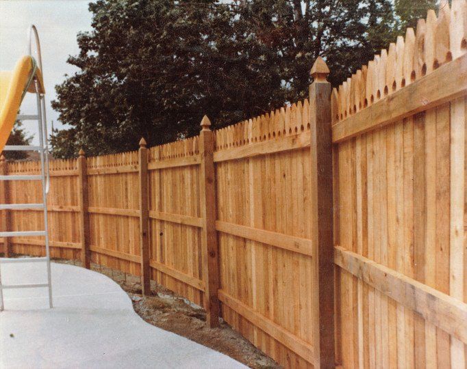 a wooden fence with a yellow slide in the background