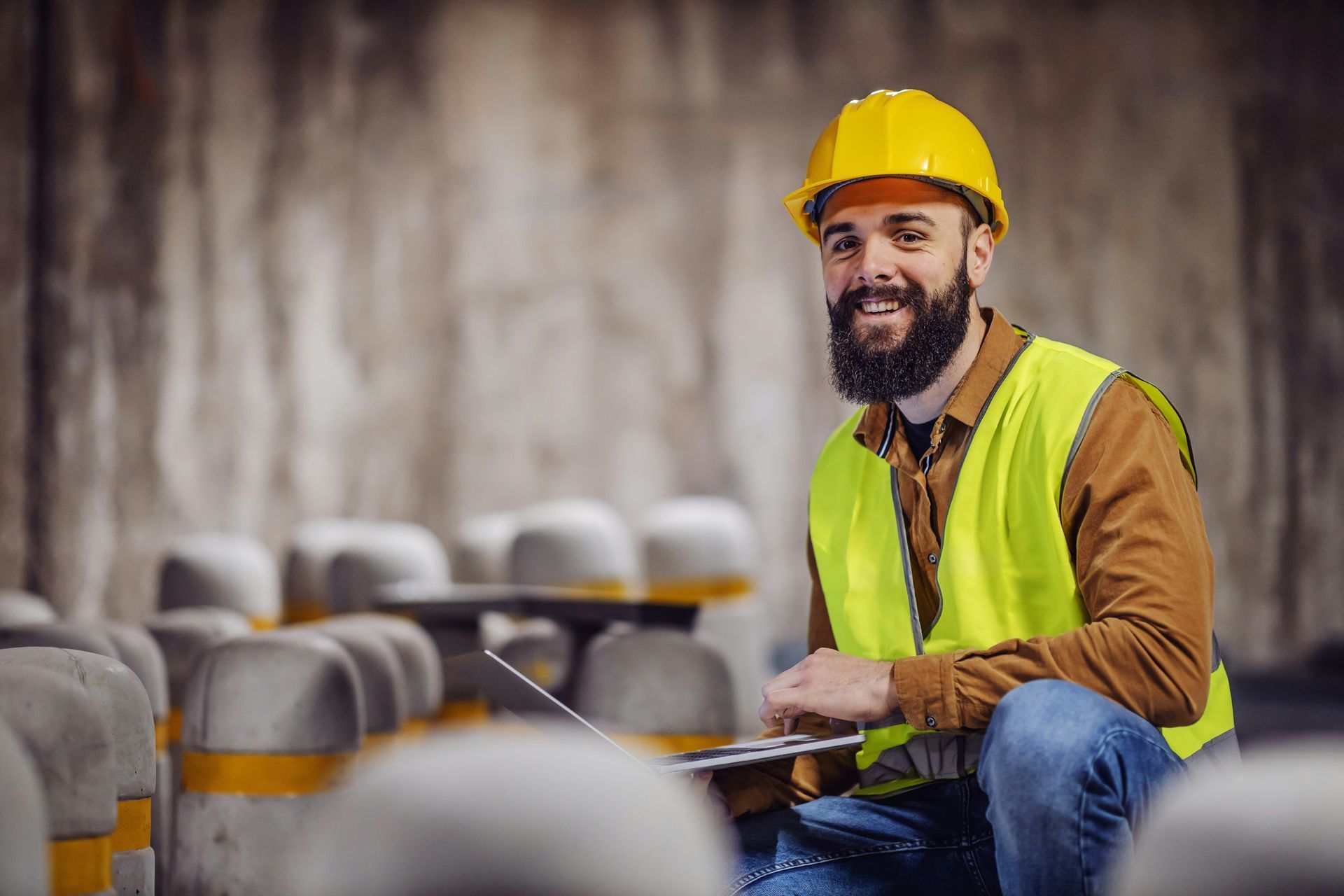 A man wearing a hard hat and safety vest is sitting on the floor.