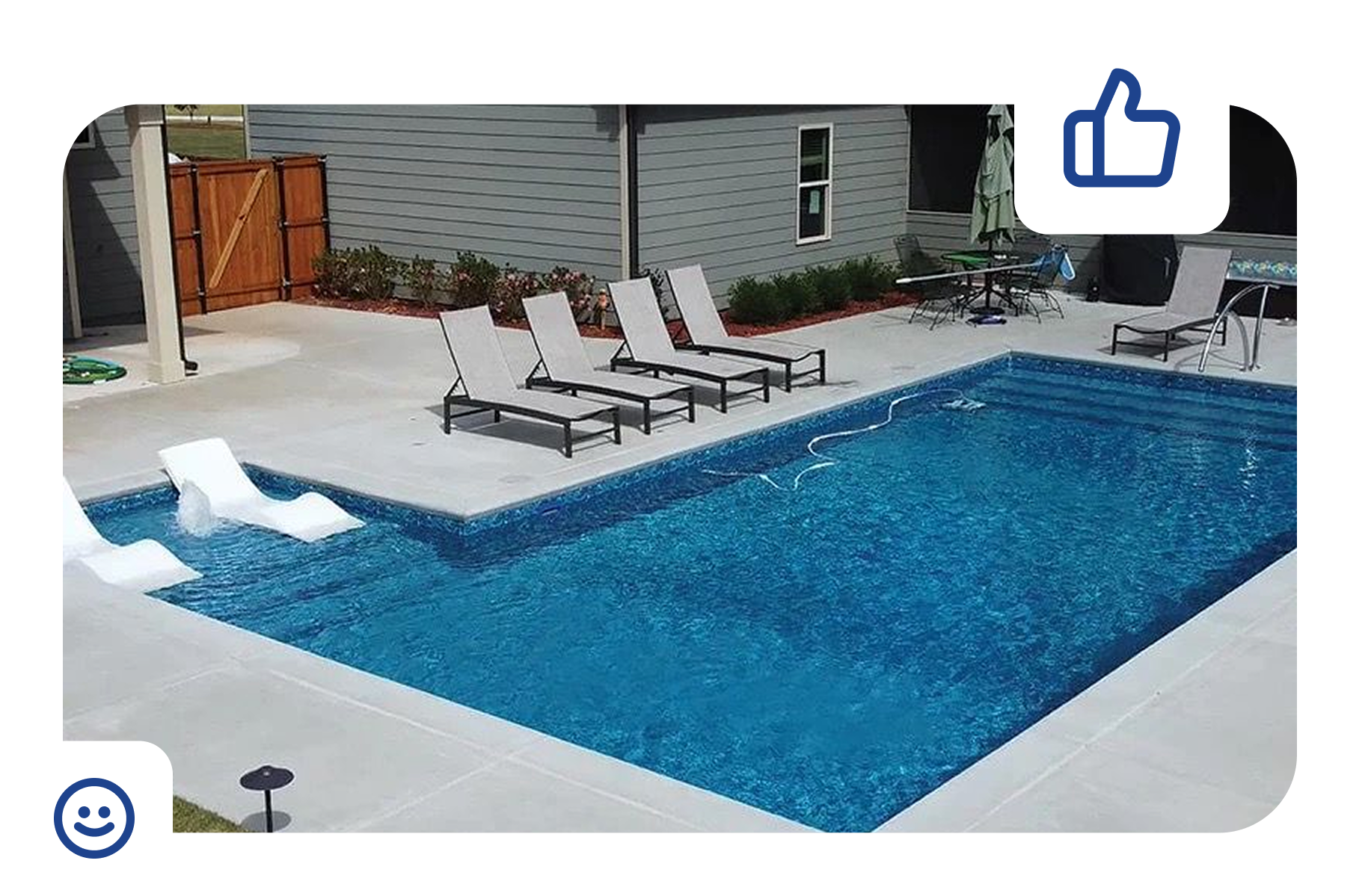 Blue-tiled swimming pool surrounded by a concrete deck, set against a backdrop of green hedges.