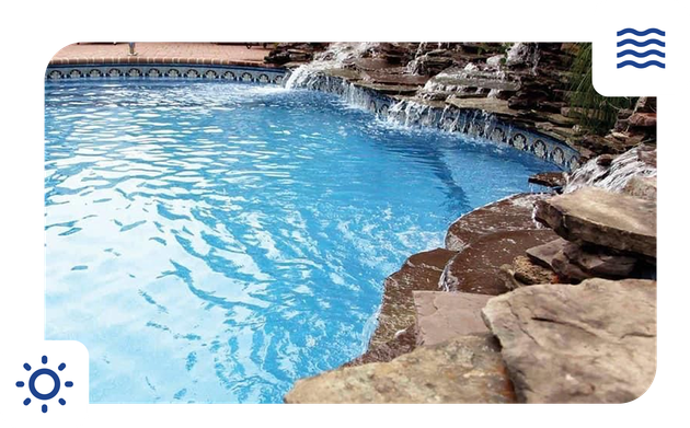 Pool with waterfall feature and blue water, surrounded by rocks.