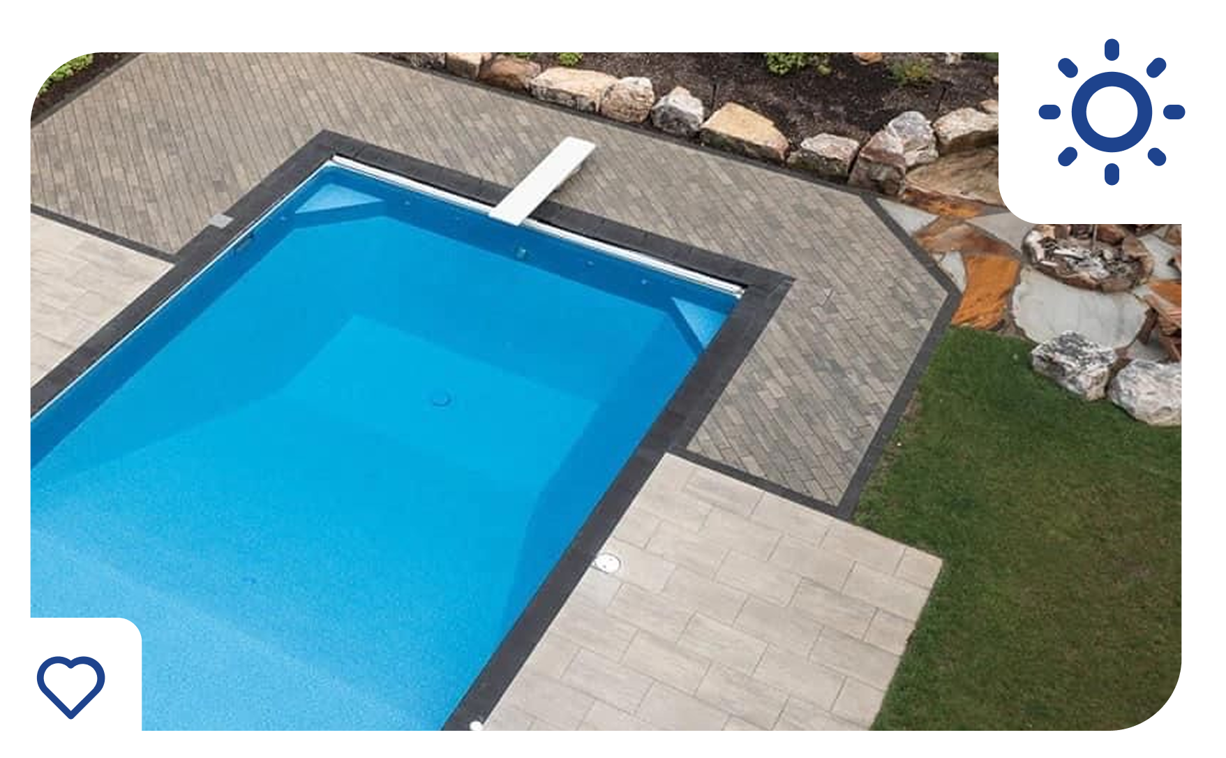 Swimming pool with a blue interior, surrounded by gray paving stones and green grass.
