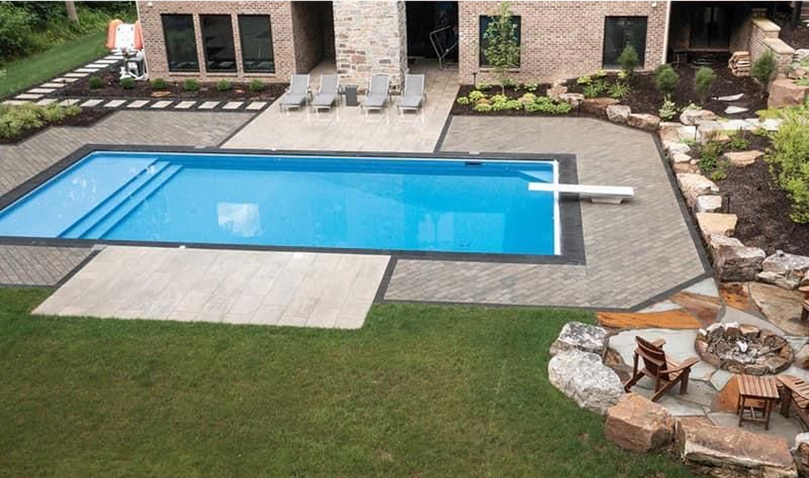 Backyard with rectangular pool, patio, lawn, landscaping, and a fire pit.