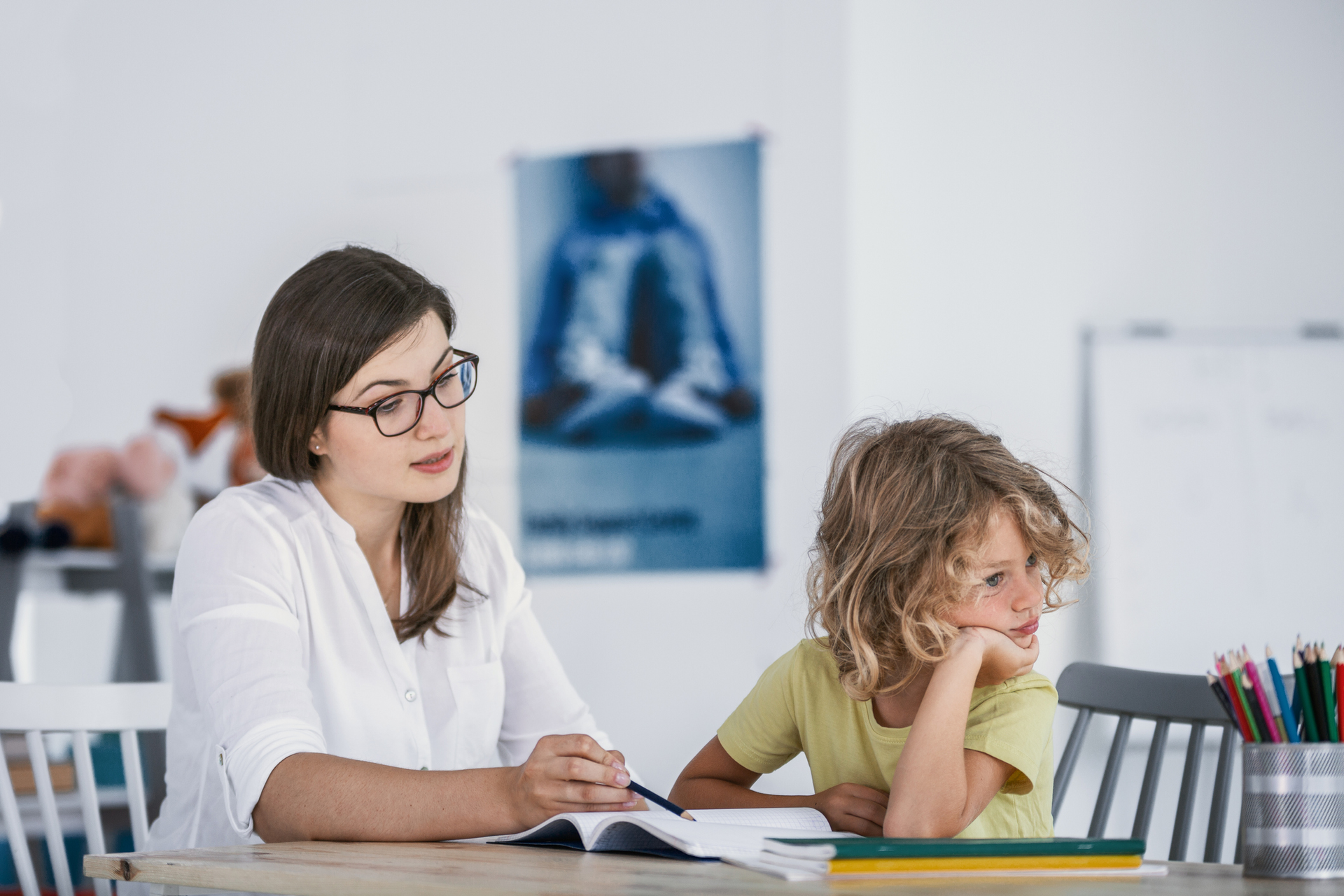 A bored child refuses to cooperate with his counselor while doing homework.