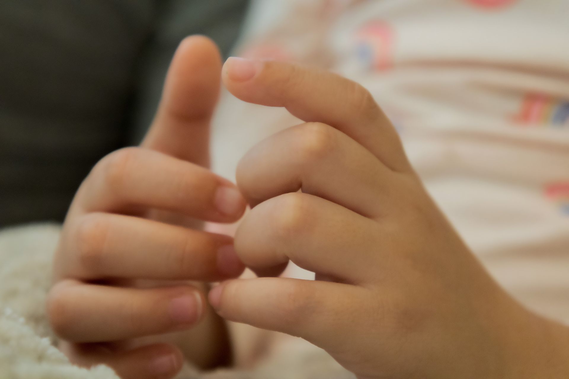 Close-up of a child's hands with fingers intertwined.