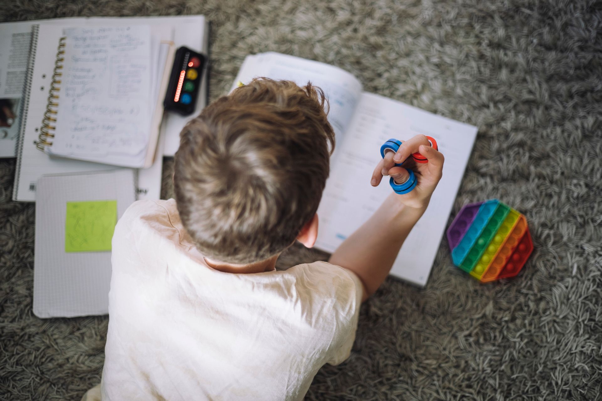 A young boy is sitting on the floor playing with a fidget toy.