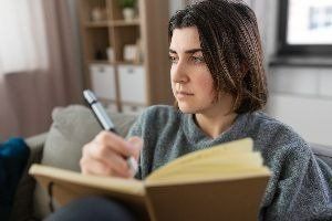 Woman on Sofa Writing on Her Journal – Anchorage, AK – Counseling Solutions of Alaksa LLC