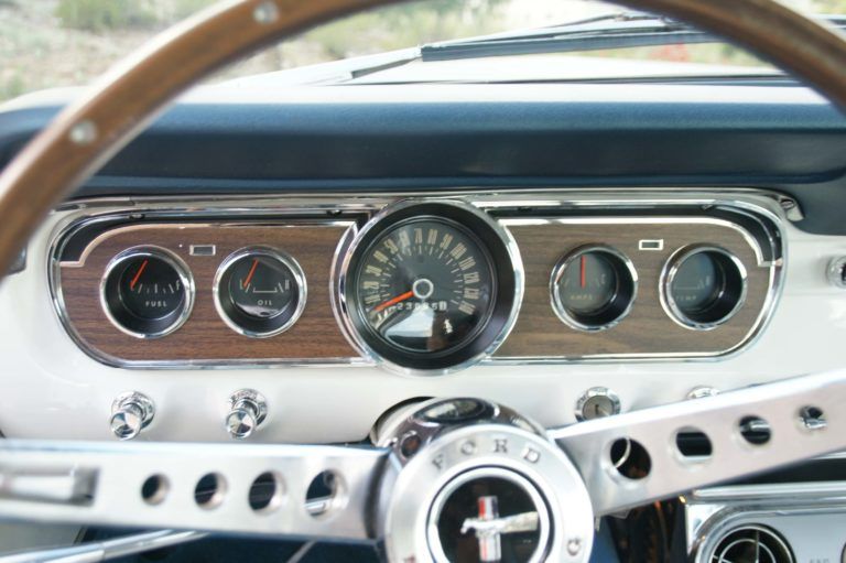 The dashboard of a ford mustang with a wooden steering wheel