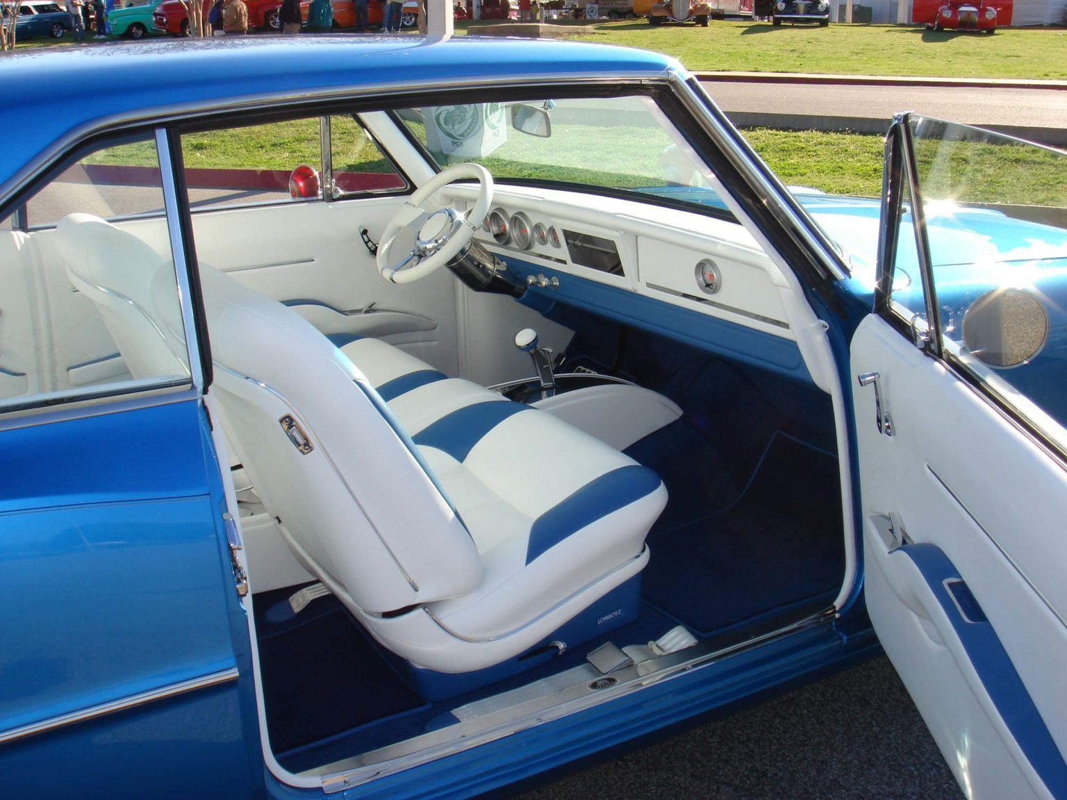The inside of a blue and white car with the door open