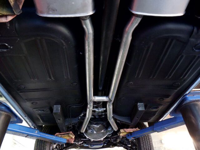 A close up of the underside of a car with exhaust pipes.