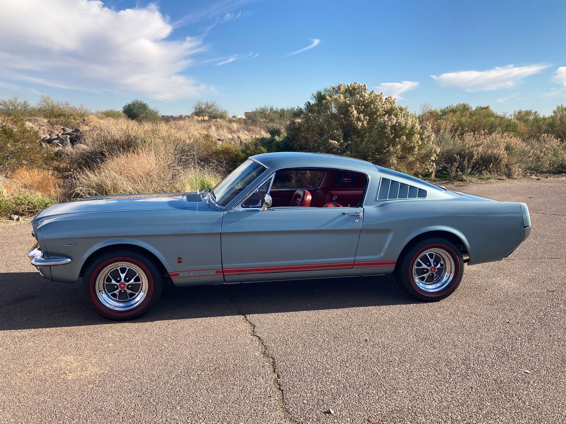 A light blue mustang is parked on the side of the road.