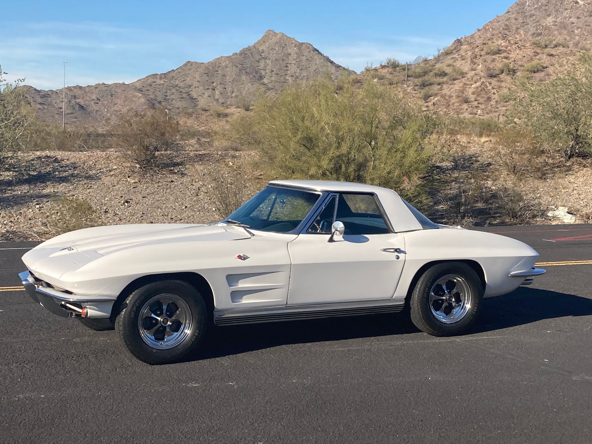 A white corvette is parked on the side of the road.