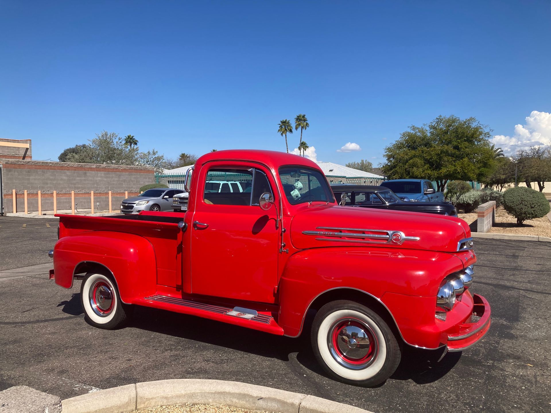 An old red pickup truck is parked in a parking lot.