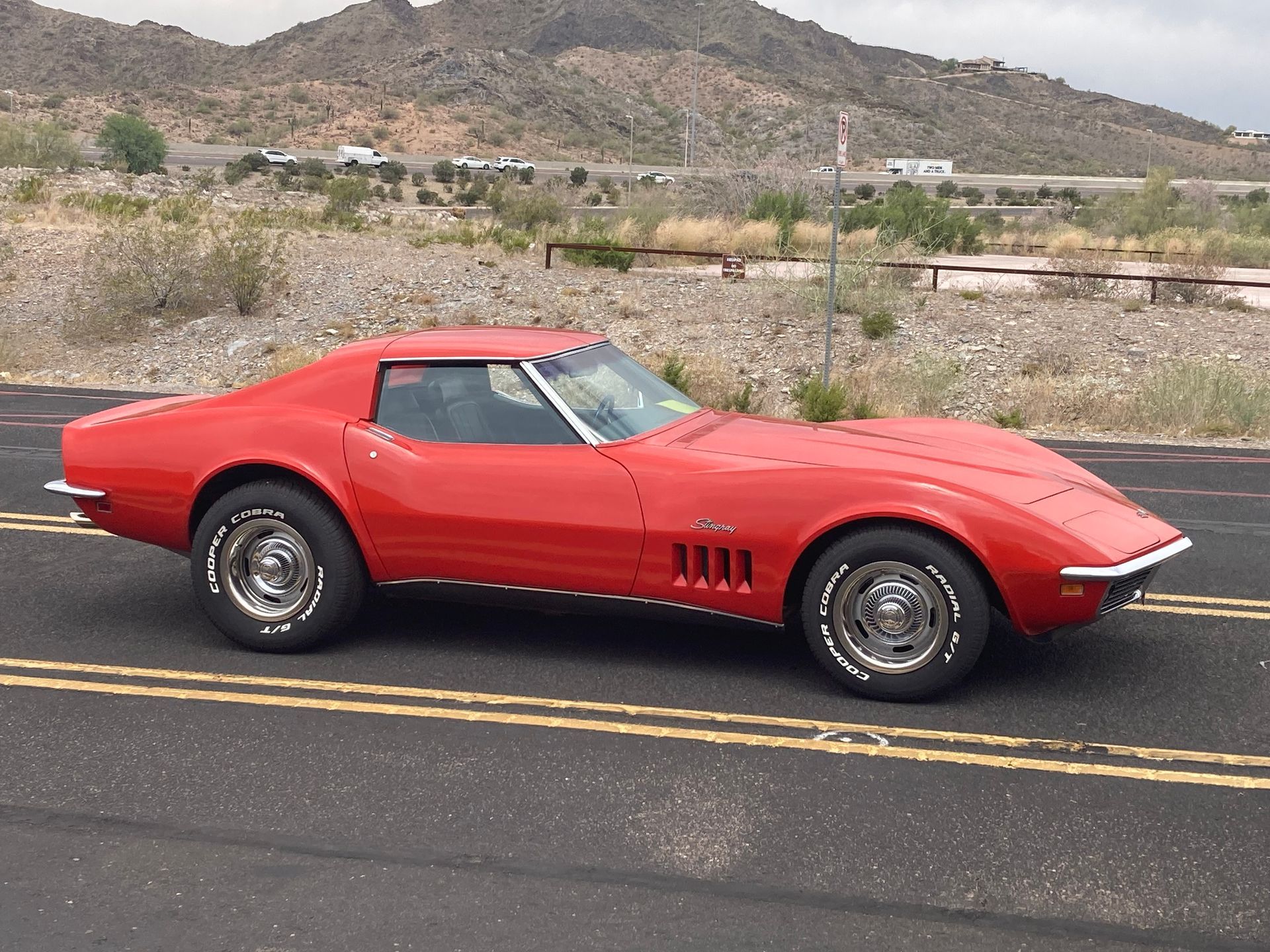 A red corvette is parked on the side of the road