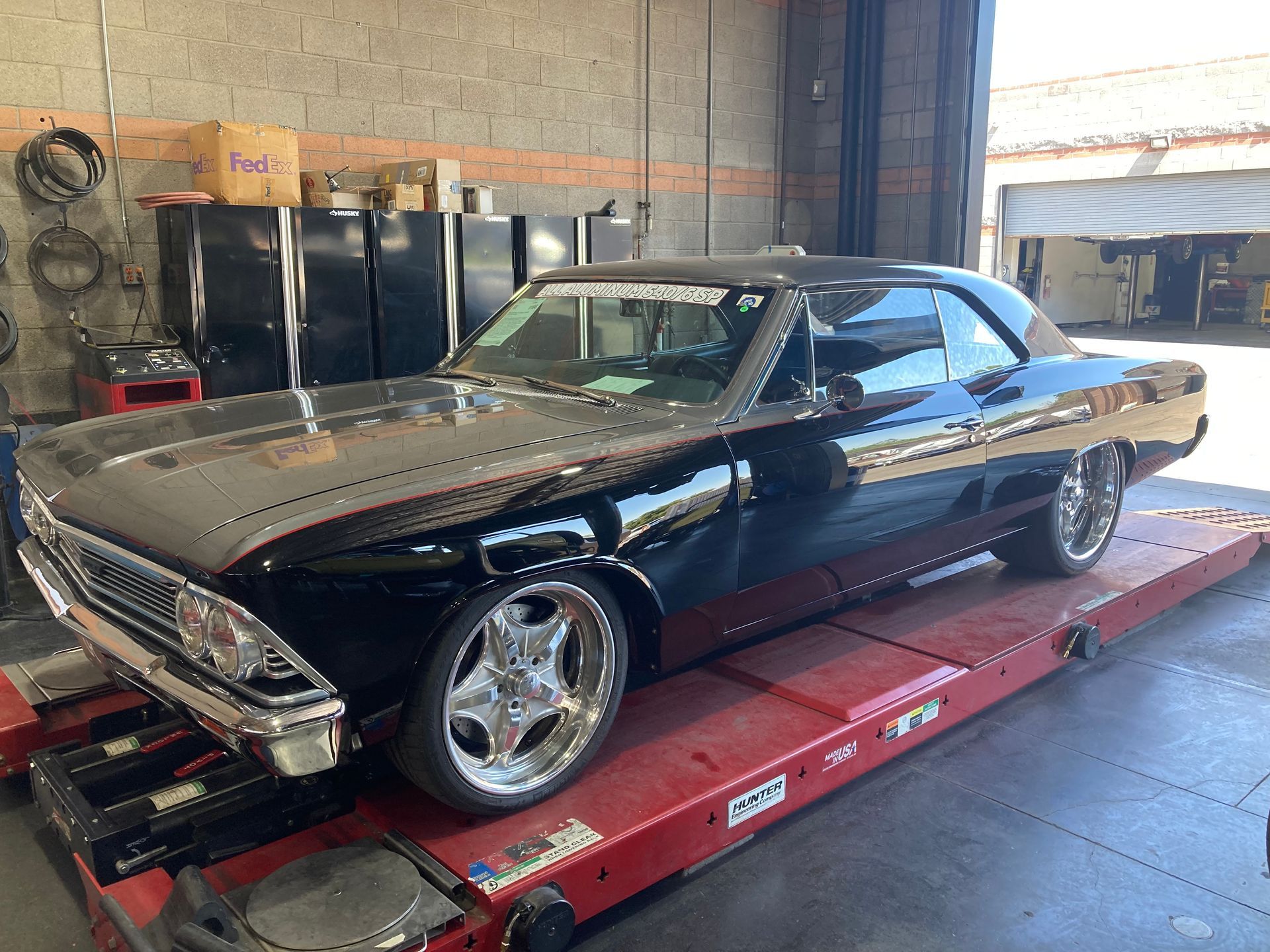 A black car is parked on a red ramp in a garage.
