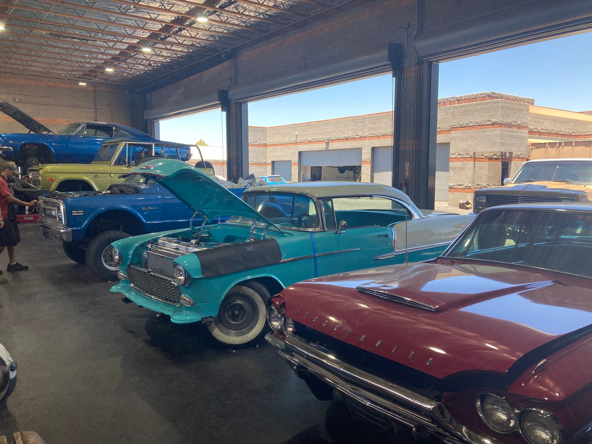 A row of old cars are parked in a garage.