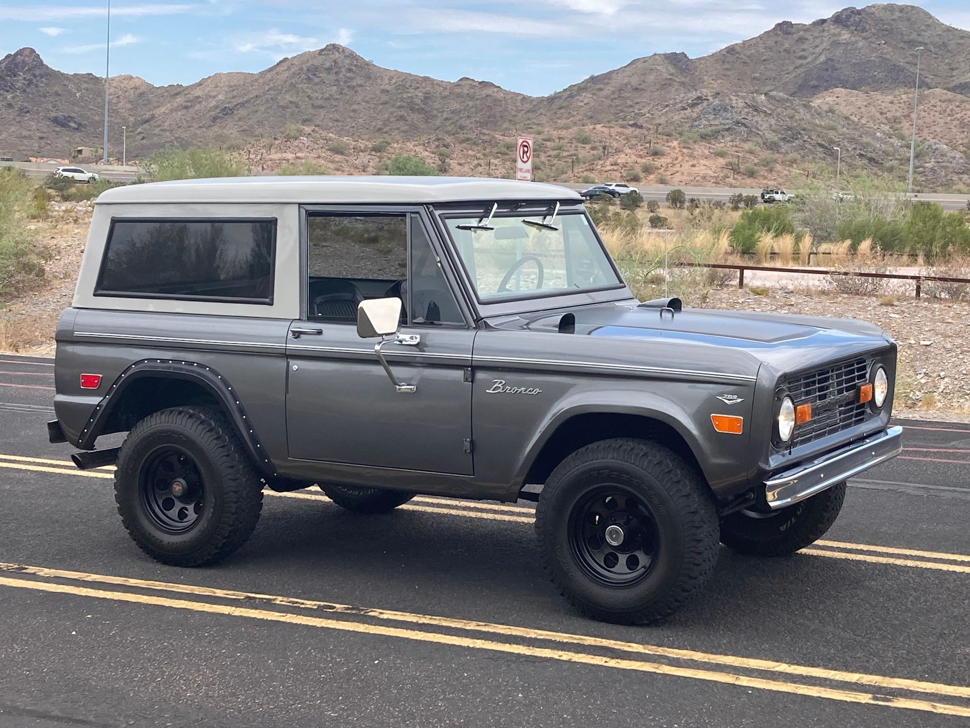 A gray ford bronco is parked on the side of the road.