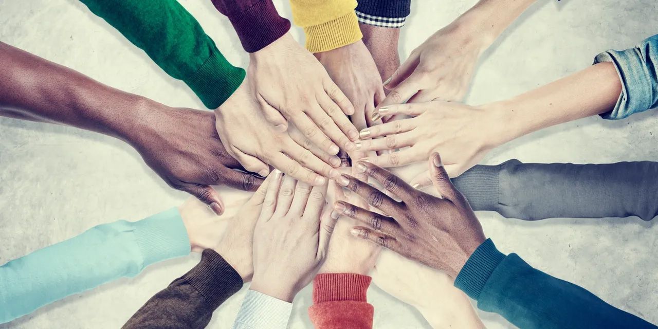 Hands of various skin tones joined together in a circle, symbolizing unity and teamwork.