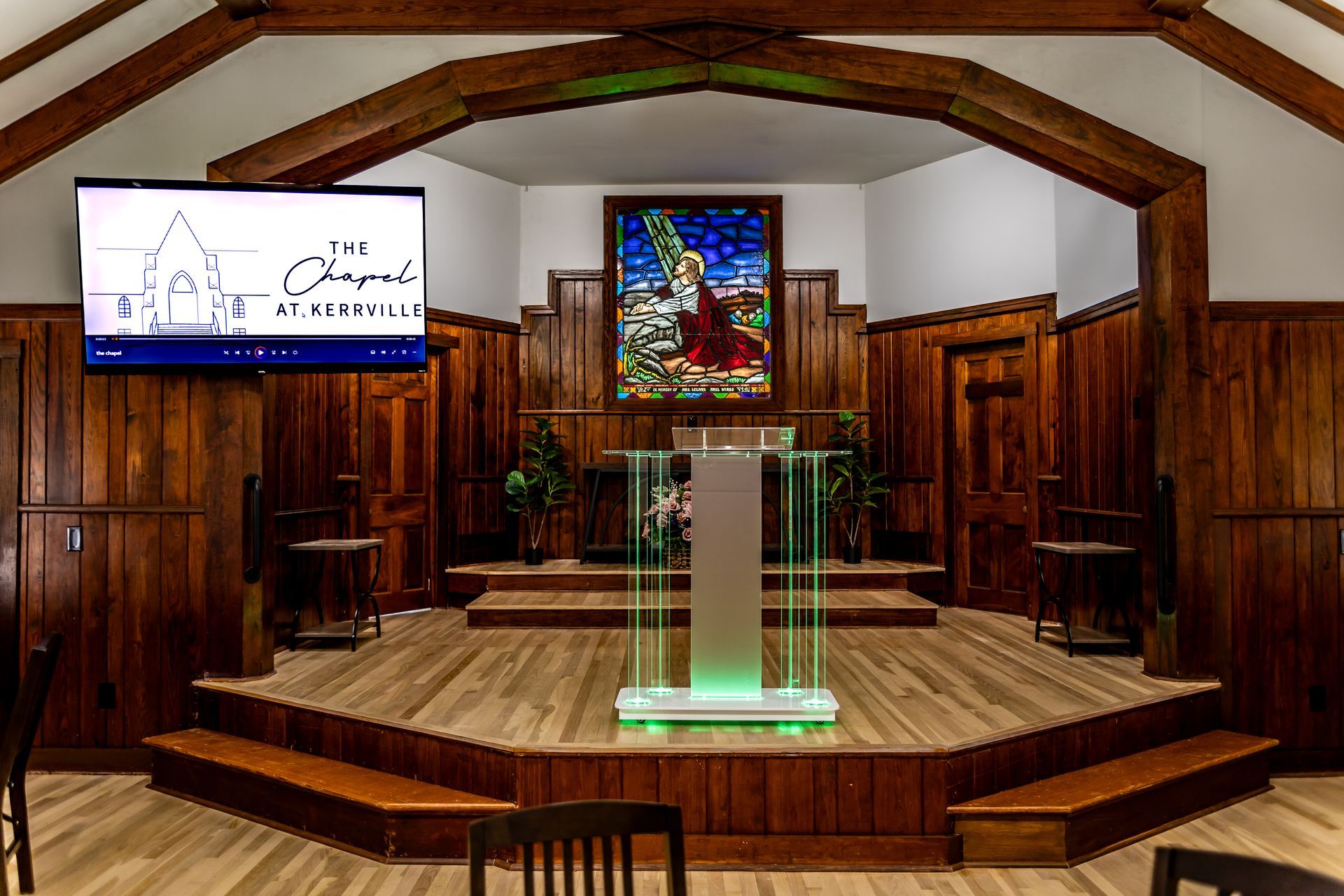 A computer monitor sits in a church, displaying a photo of a bride and groom standing before a carousel.