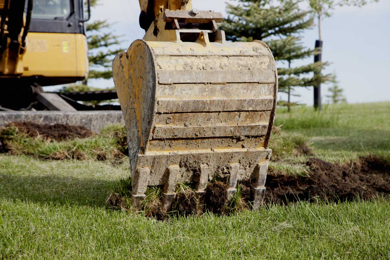 backhoe digging up fresh green grass