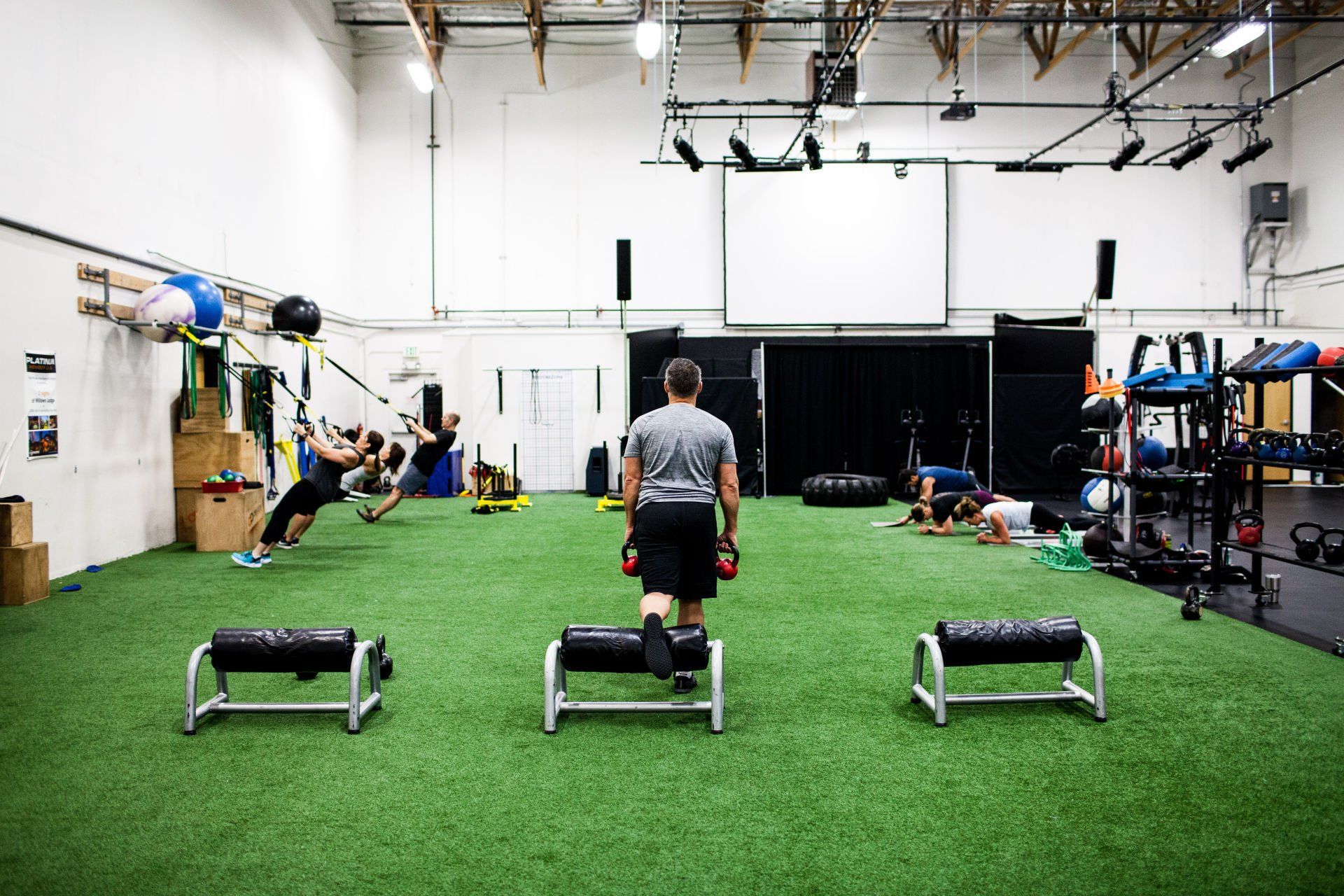 Gym with people working out on artificial turf; exercise equipment visible.