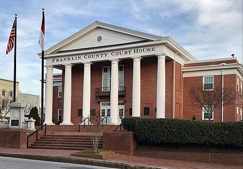 Franklin County Courthouse with white columns, red brick, and flags.