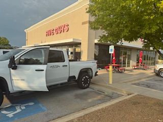 White pickup truck parked at Five Guys restaurant entrance; accessible parking spot.