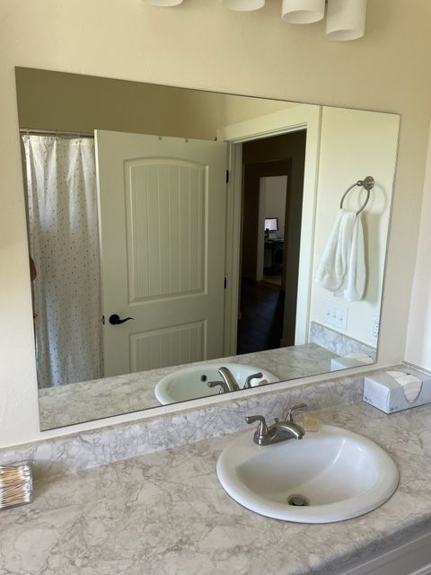 Bathroom with large rectangular mirror above a sink; white towel, door, and tissue box visible.