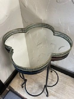 Clover-shaped side table with a mirrored top and black metal base.