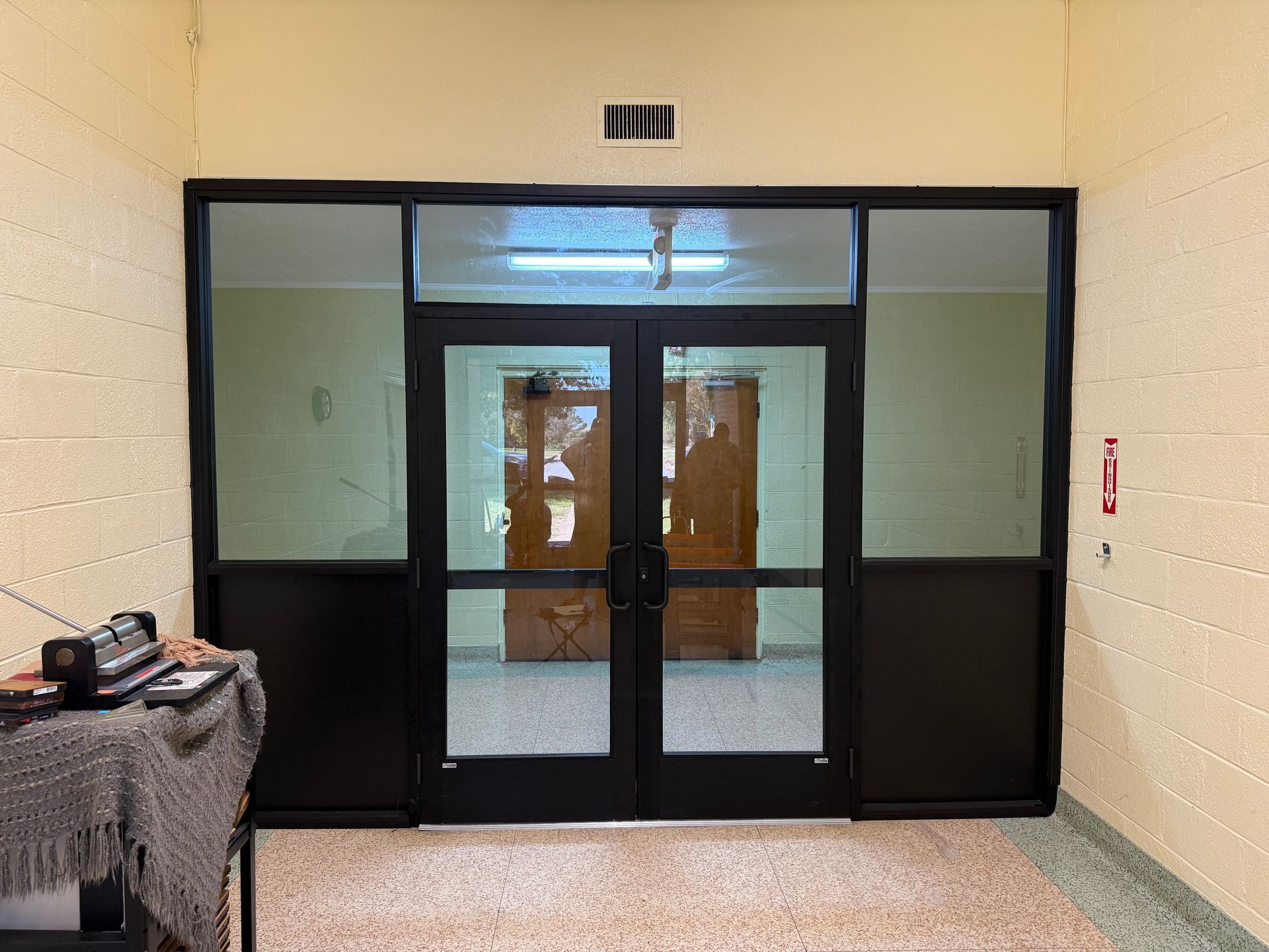 A doorway with black frames and glass panels, leading to an interior with another door visible.