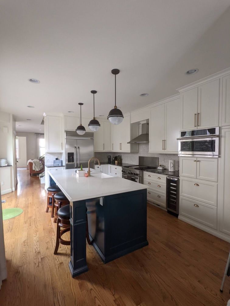 A kitchen with white cabinets and a large island in the middle.