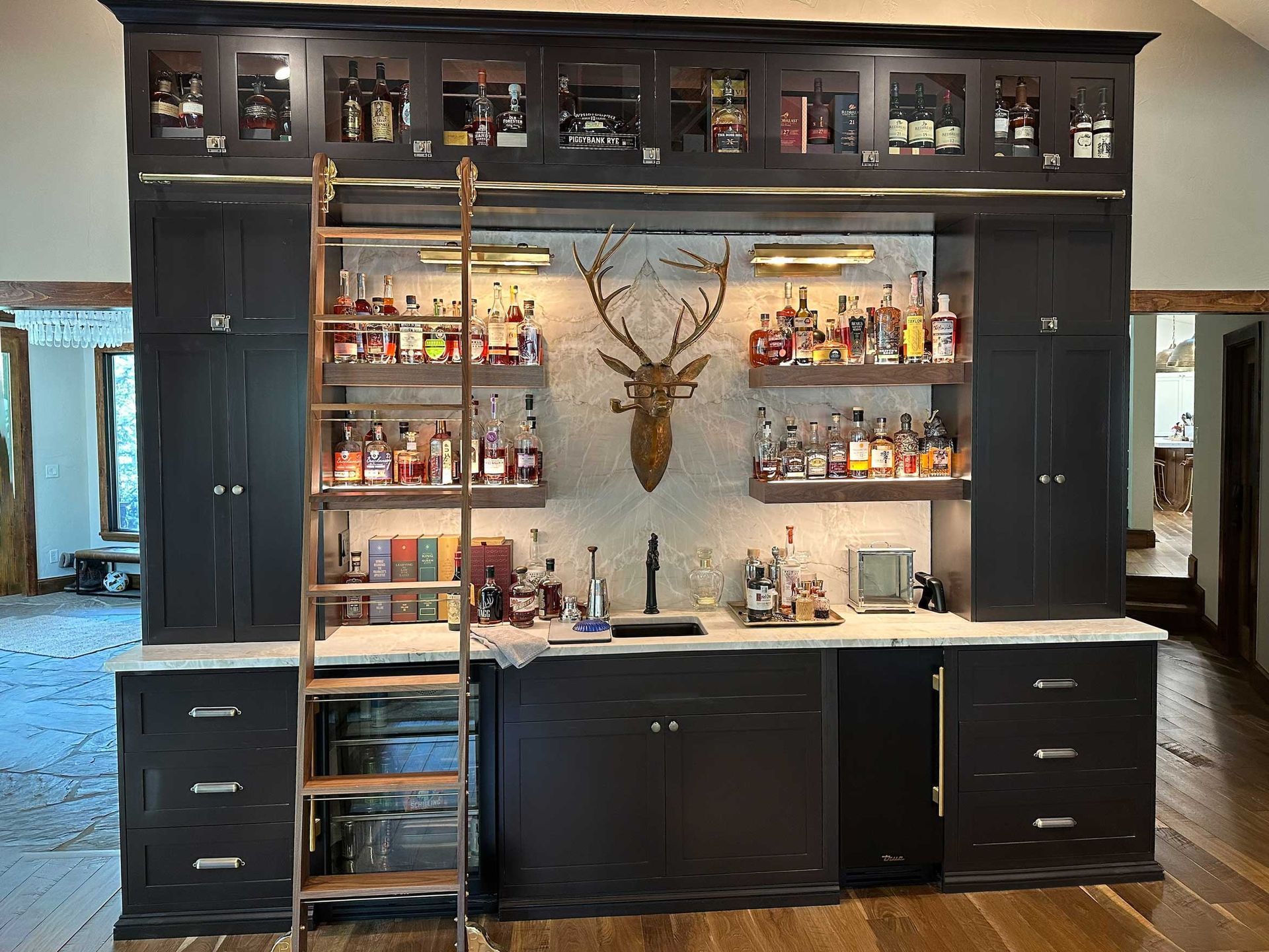 A bar with a ladder and a deer head on the wall