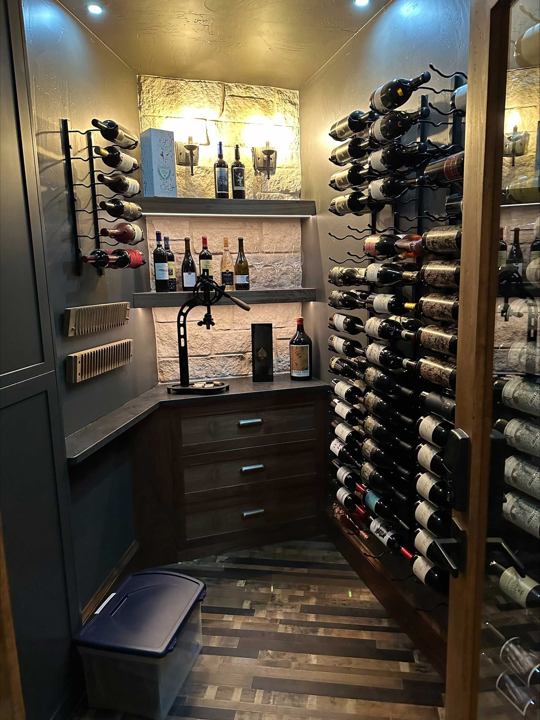 A wine cellar filled with lots of wine bottles and glasses.