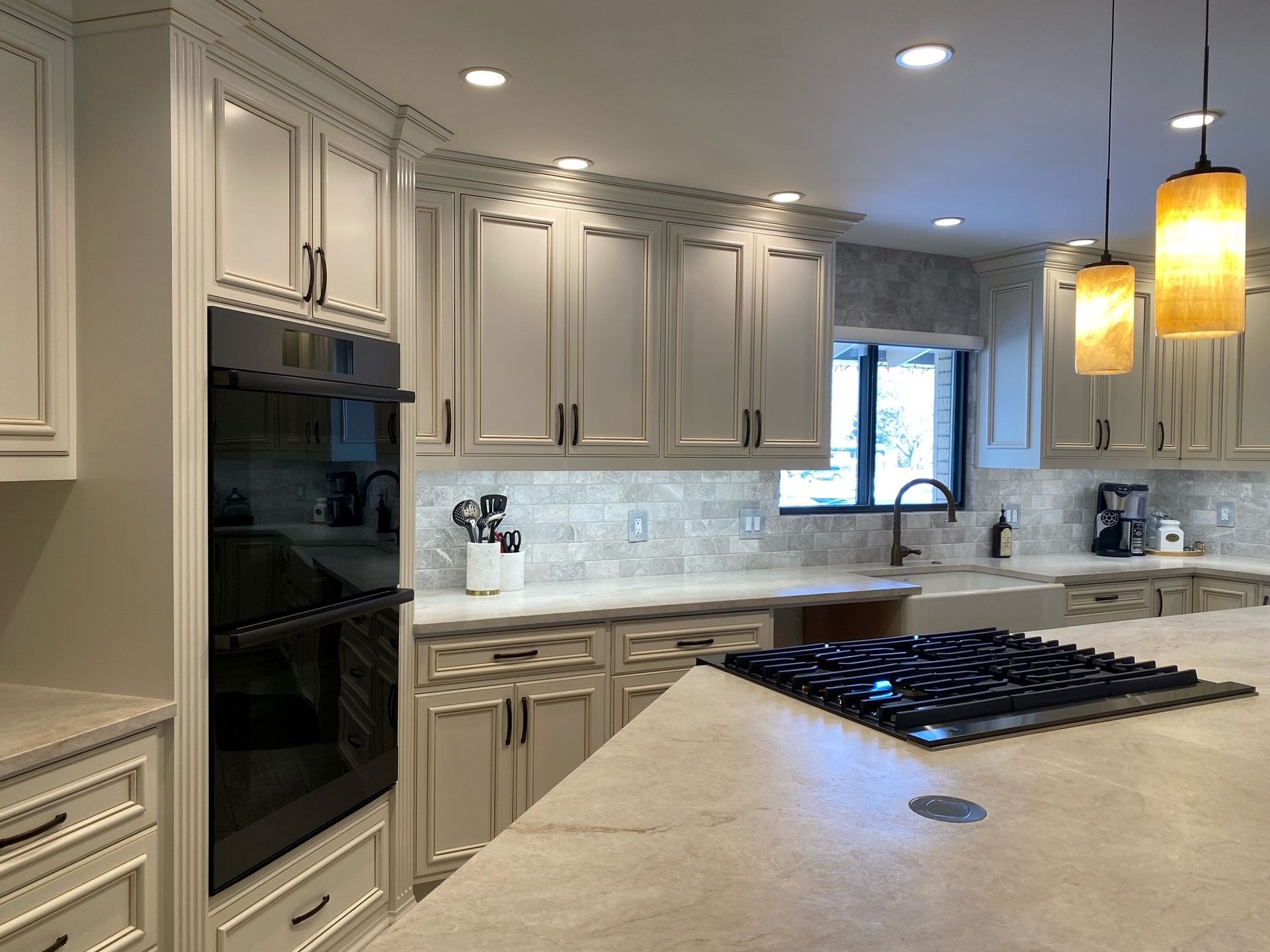 A kitchen with white cabinets , a stove top oven , a sink , and a large island.